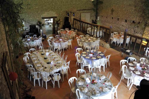 Élégante salle de banquet du Domaine De Puyrousse avec tables rondes, chaises blanches et mise de table raffinée à Villetoureix.
