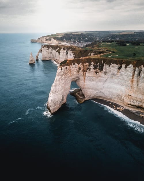 Dramatic white chalk cliffs with natural arch over turquoise sea near La Chapelle-sur-Dun, Normandy