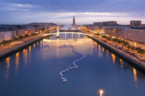 Illuminated canal at twilight with bridges and historic buildings reflecting in water near La Chapelle-sur-Dun, France