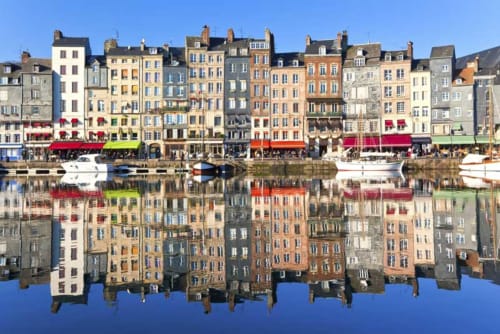 Colorful waterfront buildings reflected in calm blue water at a French coastal harbor town near La Chapelle-sur-Dun