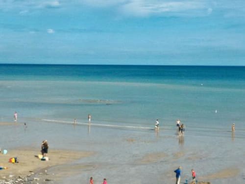 Sunny beach day with families wading in clear turquoise water near Chalet Du Bel Event, La Chapelle-sur-Dun