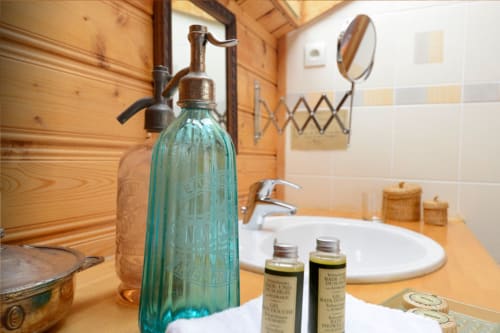 Zone lavabo à l'Auberge Nemoz avec siphon à soda vintage, produits de bain et miroir rond dans ce gîte de montagne français