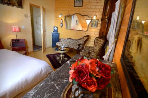 Meridian room at Auberge Nemoz with bed, fireplace, floral arrangement, rustic pine walls
