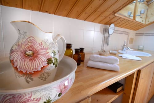 Auberge Nemoz bathroom in Melusine room with floral pitcher, towels, and wooden fixtures