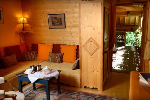 Levant room at Auberge Nemoz with wooden walls, red and orange seating, blue table, and balcony access to mountain views