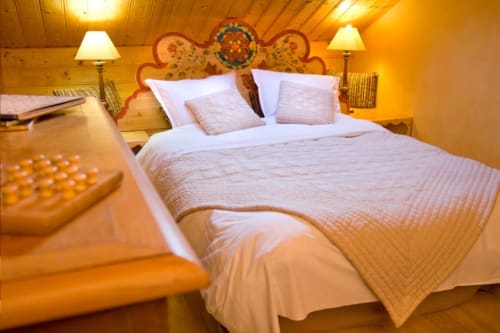 Chambre Levant à l'Auberge Nemoz avec lit queen-size, plafond en bois, tête de lit décorée et éclairage chaleureux