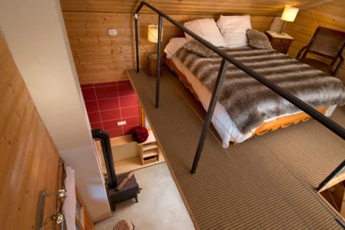 Chambre cosy en mezzanine à l'Auberge Nemoz Le Petit Chalet avec poutres, rampes métalliques et plaids en fourrure