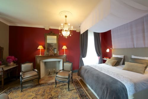 Suite Opera au Château de Baylac : chambre élégante aux murs rouges, cheminée, lustre et lit queen à Bugnein