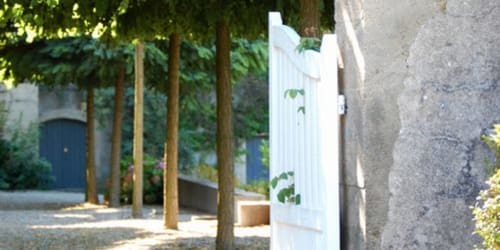 Binnenplaats van hotel Moulin Renaudiots in Autun met houten palen, wit hek en stenen muren