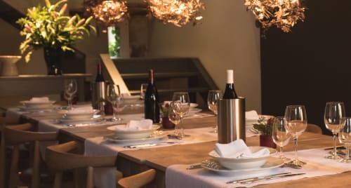 Elegant dining table at Moulin Renaudiots in Autun with wine glasses, place settings, and copper pendant lights