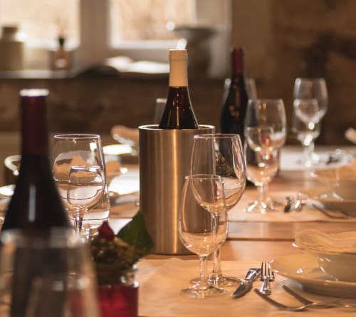 Elegant dining setup at Moulin Renaudiots with wine bottles, glasses, and place settings on wooden table