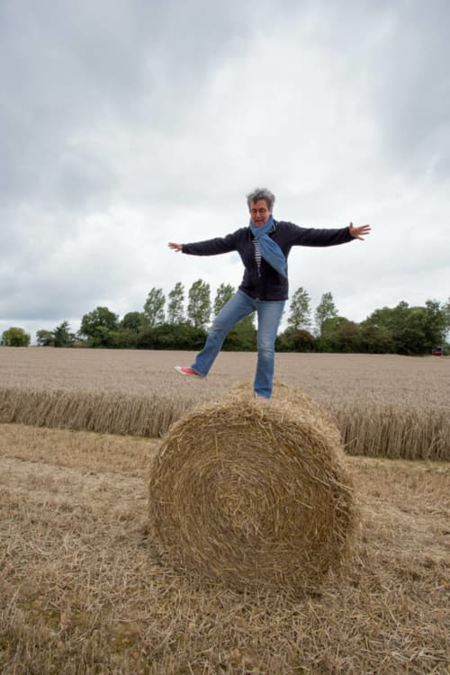 Personne qui saute sur une botte de foin dans un champ rural normand près de Port-en-Bessin