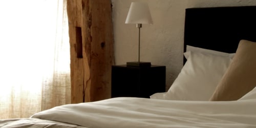 Slaapkamer Rolin van Moulin Renaudiots met bed met witte linnen, zwart hoofdeinde en bedlampje in Autun