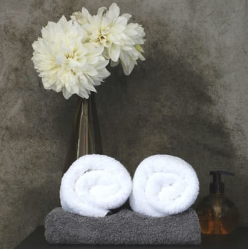 Witte opgerolde handdoeken en roomwitte dahliaflowers in een vaas in hotel Moulin Renaudiots, Autun
