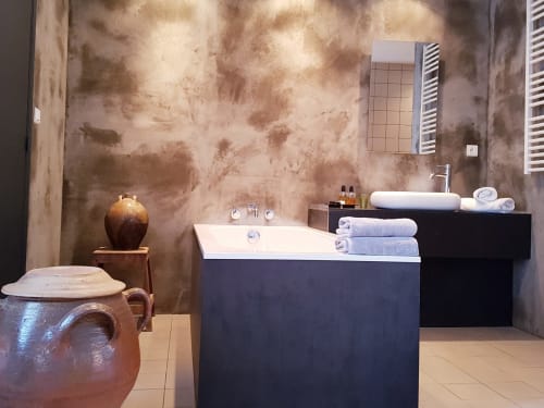 Luxe badkamer in Moulin Renaudiots in Autun met zwart bad, rustieke textuurmuren en opgerolde handdoeken