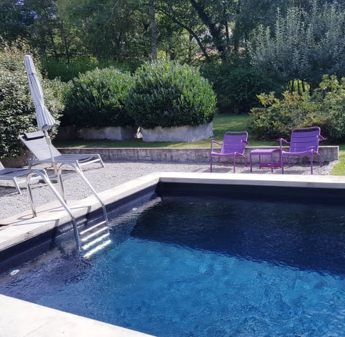 Zwembad van hotel Moulin Renaudiots in Autun, Frankrijk, met ligstoelen en weelderige tuinen