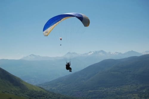 Parapentiste planant au-dessus des montagnes verdoyantes près du Château de Baylac à Bugnein, France