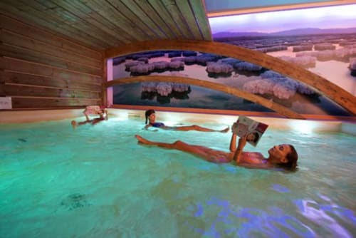 Clients détendus dans le bassin thermal du spa Château de Baylac avec fresques paysagères, Bugnein France