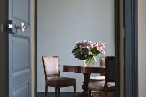 Élégante salle à manger du Château de Baylac avec chaises anciennes, table en bois et fleurs roses fraîches dans la Suite Lapis-Lazuli