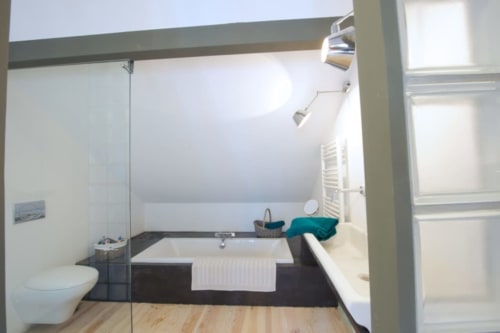 Salle de bains moderne de la Suite Vivaldi au Château de Baylac avec baignoire profonde, toilettes et équipements contemporains à Bugnein, France