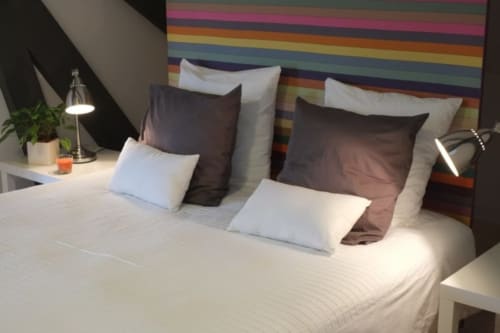 Chambre Suite Vivaldi du Château de Baylac avec tête de lit rayée multicolore, literie blanche et décoration moderne à Bugnein