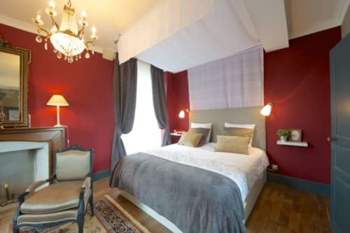 Chambre Suite Opera du Château de Baylac avec murs rouges, lustre élégant et vue sur les montagnes à Bugnein