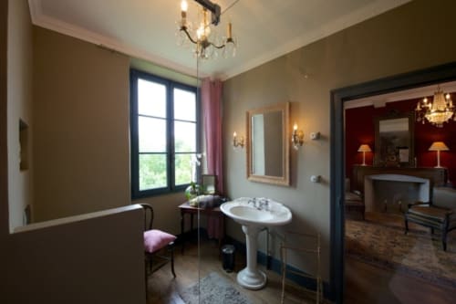 Salle de bain Suite Opéra du Château de Baylac avec lavabo sur piédestal, lustre en cristal et vue sur les montagnes