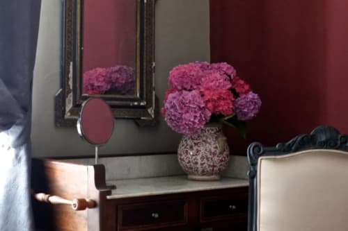 Élégante coiffeuse avec hortensias roses en vase décoratif, miroir et mobilier en bois foncé à la Suite Opéra du Château de Baylac,