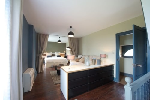 Chambre Familiale Racine du Château de Baylac avec lit king-size, vanité îlot noir, luminaires suspendus et vue sur jardin à Bugnein