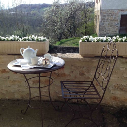 Wrought iron table and chairs on terrace at Manoir De Rieuzal with white flowers and mountain views