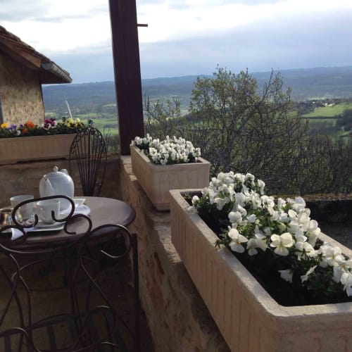 Terrasse with white flowers overlooking Loubressac valley, wrought iron seating, mountain views at Manoir De Rieuzal
