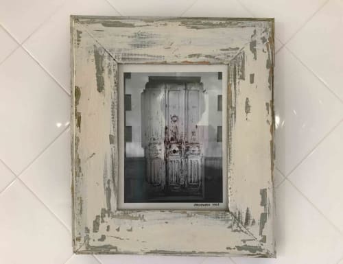 Weathered white frame displays distressed wooden doors, rustic décor in Manoir De Rieuzal boutique hotel, Loubressac