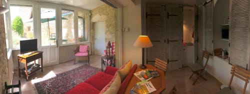Bright sitting room in Camomille room at Manoir De Rieuzal with red sofa, terrace views, TV, lamp and mountain landscape