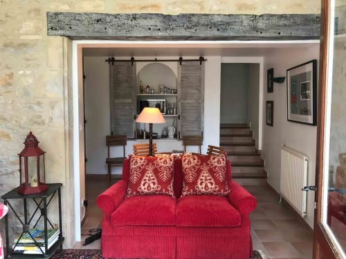 Red sofa in Verveine room at Manoir De Rieuzal B&B, Loubressac, with arched shelving and wooden beams visible in background