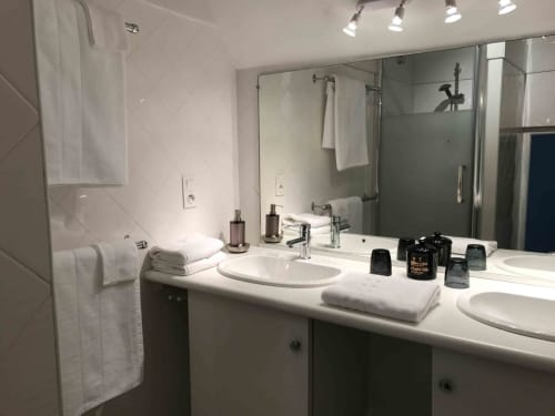 Modern bathroom at Manoir De Rieuzal with double sinks, shower enclosure, and white amenities in Loubressac