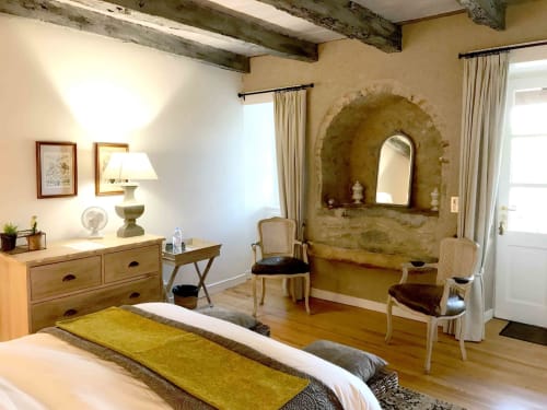 Rustic bedroom at Manoir De Rieuzal with exposed beams, arched stone niche, and period furnishings in Loubressac