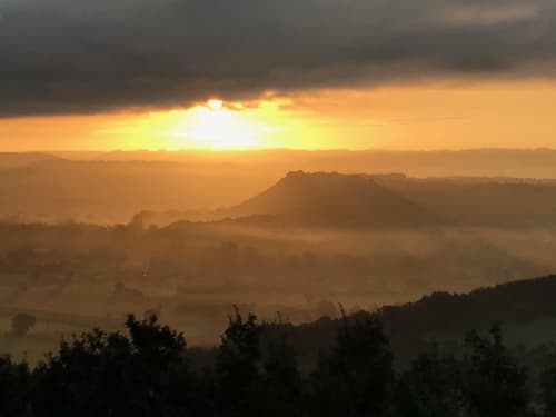 Golden sunset over misty valleys and mountain peaks near Loubressac, France