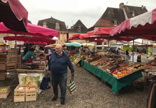 Outdoor market with red awnings in Loubressac, France near Manoir De Rieuzal