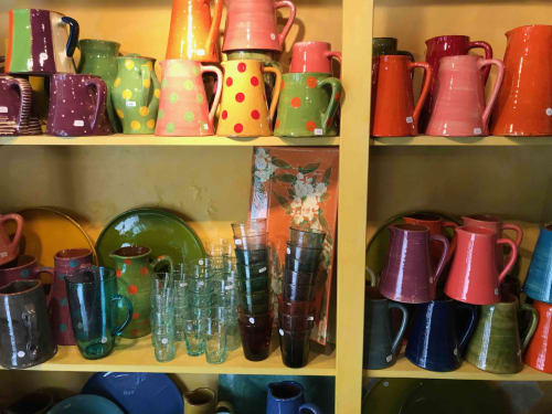 Colorful ceramic pitchers and glassware displayed on shelves at Manoir De Rieuzal in Loubressac, France