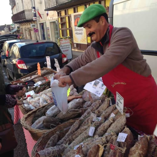 Vendor selling regional sausages at market in Loubressac, France near Manoir De Rieuzal