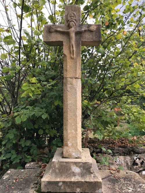 Stone cross monument surrounded by greenery at Manoir De Rieuzal in Loubressac, France