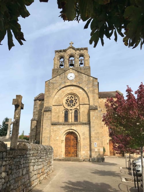 Stone church with clock tower in Loubressac, France near Manoir De Rieuzal B&B, framed by autumn foliage