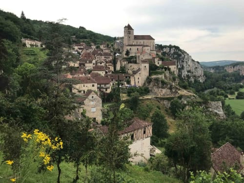 Medieval village of Loubressac perched on cliffs with stone church tower, Manoir De Rieuzal B&B nestled among