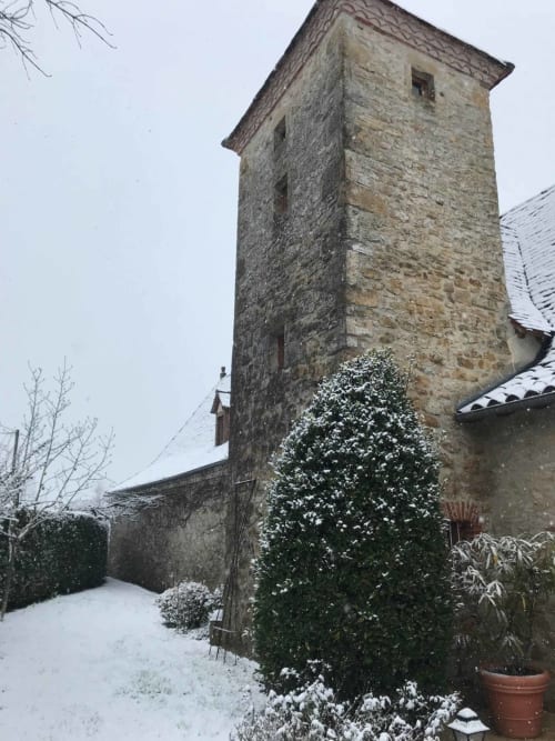 Medieval stone tower at Manoir De Rieuzal in snowy Loubressac, France, with ivy-covered walls