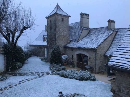 Manoir De Rieuzal stone manor with turret and snowy courtyard in Loubressac, France winter scene
