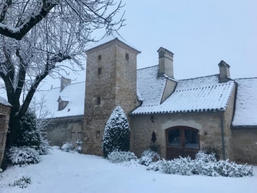 Manoir De Rieuzal in Loubressac covered in snow with stone tower and winter gardens