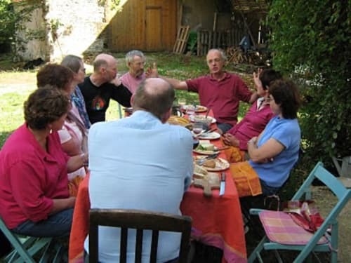 Group gathering at outdoor table in Loubressac, Manoir De Rieuzal backyard garden with food and conversation
