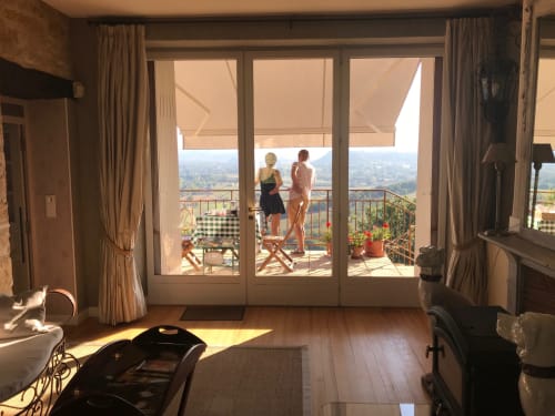Sunny bedroom at Manoir De Rieuzal B&B in Loubressac with balcony, two guests, and panoramic countryside views
