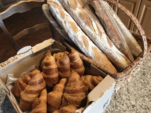 Fresh croissants and baguettes in baskets at Manoir De Rieuzal, a French bed and breakfast in Loubressac