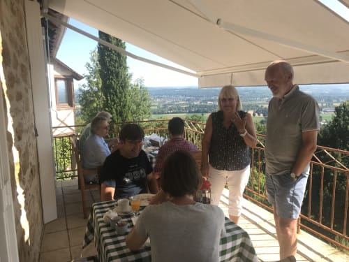 Guests enjoying outdoor terrace at Manoir De Rieuzal with panoramic valley views in Loubressac, France